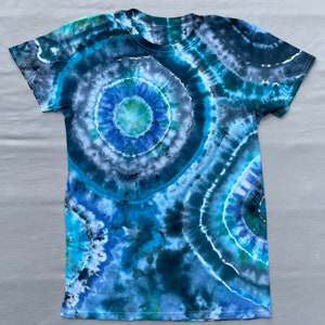 May include: A tie-dye t-shirt with a blue, green, and black circular pattern. The shirt has short sleeves and a crew neck.