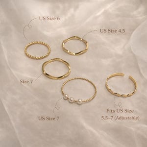May include: A collection of gold-colored rings in various designs. The rings include a twisted band, wavy bands, a band with pearls, and an adjustable ring. Sizes are US 4.5, 6, and 7. The adjustable ring fits US sizes 5.5-7.