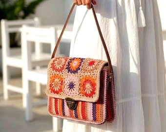 Puede incluir: Un bolso de mano rectangular de ganchillo con una solapa decorada con cuadrados de la abuela florales multicolores en tonos naranja, rosa y morado. El cuerpo del bolso muestra rayas verticales a juego, complementado con una correa de cuero marrón y un cierre.
