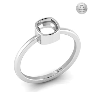May include: A sterling silver ring with a square bezel setting. The ring has a polished finish and a delicate band. The ring is stamped with "925" on the band, indicating the silver purity. A "Real 925 Sterling Silver Guarantee" seal is in the background.