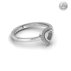 May include: A sterling silver ring with a heart-shaped design. The ring features a heart-shaped center stone surrounded by a halo of smaller stones. The ring is polished and has a shiny finish. The image also includes a Real 925 Sterling Silver Guarantee seal.