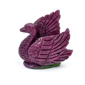 Puede incluir: Una figurita de cisne tallada en piedra de rubí con plumas detalladas y un tono rosado.