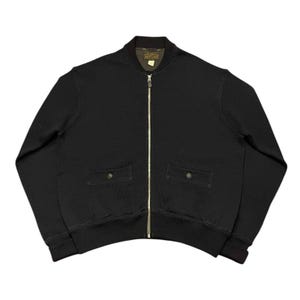 Puede incluir: Una chaqueta bomber negra con cremallera, dos bolsillos de solapa y cuello y puños de canalé.