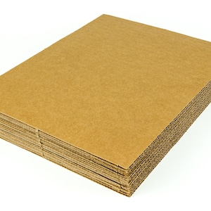 May include: A stack of new, unused corrugated cardboard sheets. The cardboard is a light brown color and has a ridged edge. The stack is rectangular and sits on a white background.