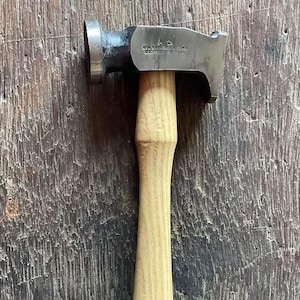 May include: A metal hammer with a wooden handle. The hammerhead is dark grey and has text that reads "GEO. BARNSLEY & SONS SHEFFIELD ENGLAND". The handle is light brown.