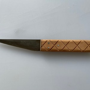 Può includere: Un piccolo coltello argentato a lama singola con manico in legno. Il manico presenta un motivo a rombi ed è in legno marrone chiaro. La lama è incisa con "A.E. BARLEY & SONS LTD."