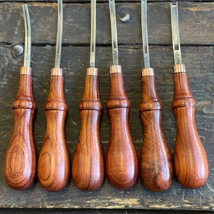 May include: Set of six leather crafting tools with wooden handles. The tools have different shaped blades and are labeled with numbers 0 through 5.