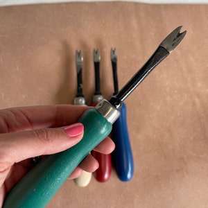 May include: Four vintage upholstery tools with wooden handles. The tools have a metal claw at the end and are green, white, red, and blue.