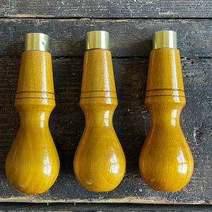 May include: Three wooden dowel tools with brass caps. The tools are yellow and have a rounded shape.