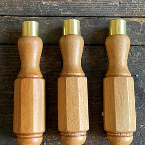 Könnte beinhalten: Drei Schraubendrehergriffe aus Holz mit Messingköpfen. Die Griffe sind achteckig und haben eine glatte, polierte Oberfläche.