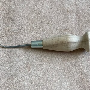 May include: A wooden-handled leather sewing awl with a curved metal needle.