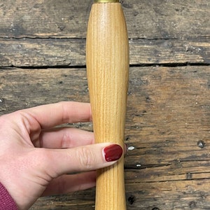Op de afbeelding: Een houten handvat voor een snijgereedschap met een messing ferrule. Het handvat is lichtbruin met een nerfpatroon.