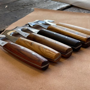 May include: A set of six wood-handled tools with metal blades. The tools have different shapes and sizes. The handles are made of different types of wood, including olive wood and walnut.