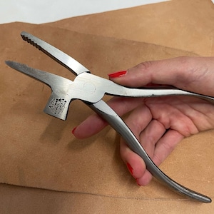 May include: A silver multi-tool with a hammer head and pliers. The tool is made by the company "A.W. FABER  MADE IN ENGLAND".