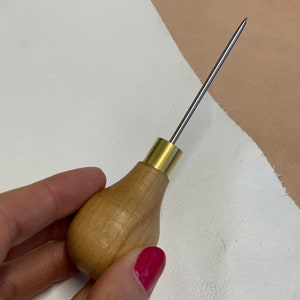 May include: A wooden-handled leather stitching awl with a brass ferrule and a sharp metal needle.