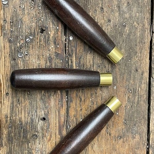May include: Three wooden handles with brass ends. The handles are dark brown and have a smooth finish.