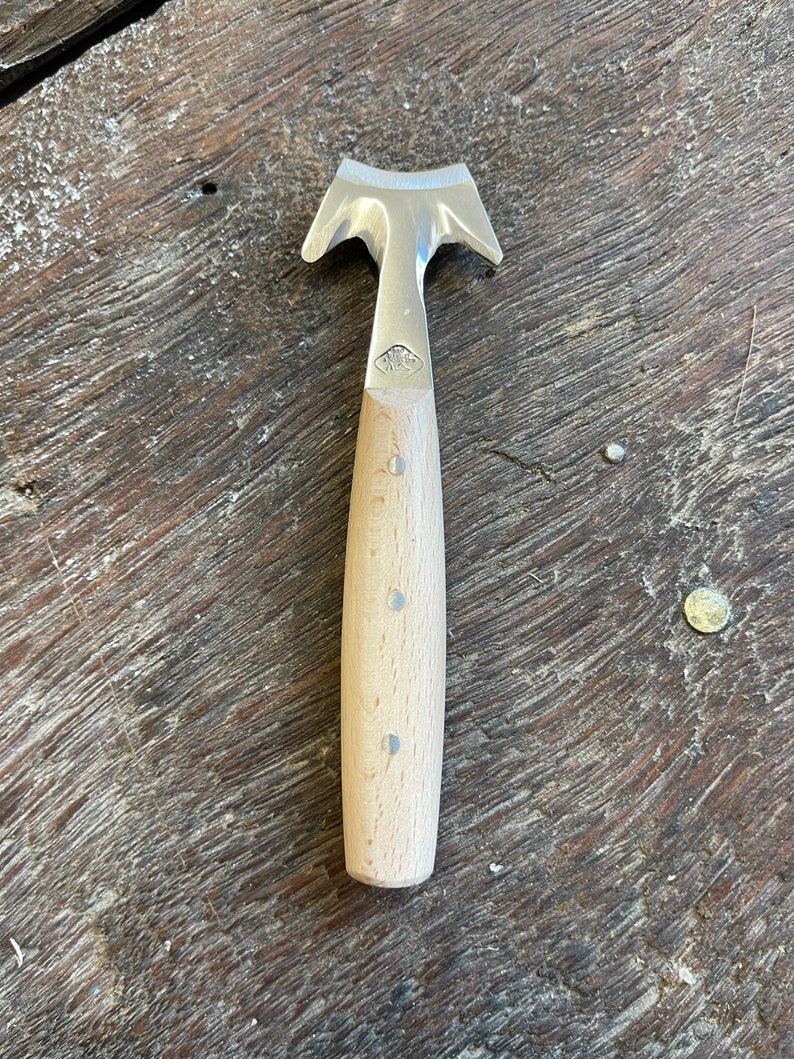 May include: A small, wooden-handled gardening tool with a three-pronged metal head. The tool is designed for weeding and transplanting.
