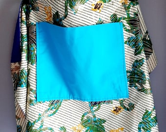 Könnte beinhalten: Eine weiße Schürze mit einer blauen Tasche und einem Blumenmuster. Die Schürze hat einen schwarzen Kleiderbügel und bindet sich in der Taille.