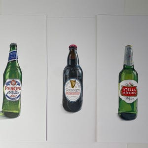 May include: Three beer bottles: Peroni, Guinness, and Stella Artois, each with its distinct label. The Peroni bottle is green with a blue and white label. The Guinness bottle is dark with a white label. The Stella Artois bottle is green with a red and white label.