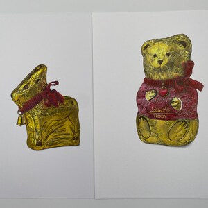 Puede incluir: Dos figuras de chocolate envueltas en papel de aluminio: un conejito dorado con una cinta y una campana rojas, y un osito de peluche dorado con un su&eacute;ter rojo con un coraz&oacute;n y la palabra "Teddy".