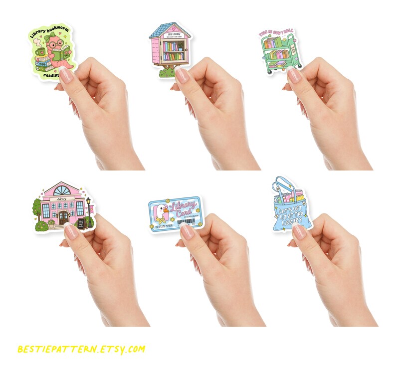 May include: A collection of colorful stickers featuring library-themed designs. The stickers include a library bookworm, a pink library building, a library cart, a library card, and a bag of books. The stickers are held in hands.