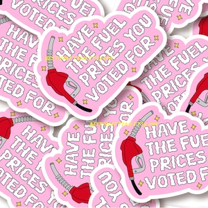以下が含まれることがあります： 「HAVE THE FUEL PRICES YOU VOTED FOR」の白文字が入ったピンク色のステッカー。赤いガソリンポンプのノズルと黄色の星のアクセントが特徴です。ステッカーはダイカットで、白い縁取りがあります。