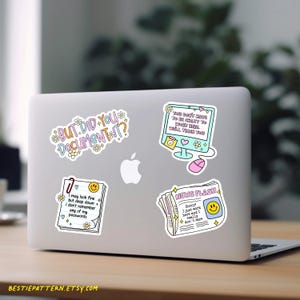 Puede incluir: Un port&aacute;til con cuatro pegatinas coloridas. Las pegatinas tienen textos humor&iacute;sticos: "BUT DID YOU DOCUMENT IT?", "YOU DON'T HAVE TO BE CRAZY TO WORK HERE, WELL TRAIN YOU", "I may look fine but deep down I don't remember any of my passwords", y "NEWS FLASH".