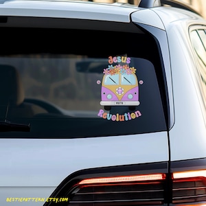Puede incluir: Un coche blanco con una pegatina en la ventana trasera. La pegatina presenta una furgoneta de dibujos animados rosa y amarilla con flores en la parte superior. El texto "Jesus Revolution" est&aacute; debajo de la furgoneta en colores arco&iacute;ris.