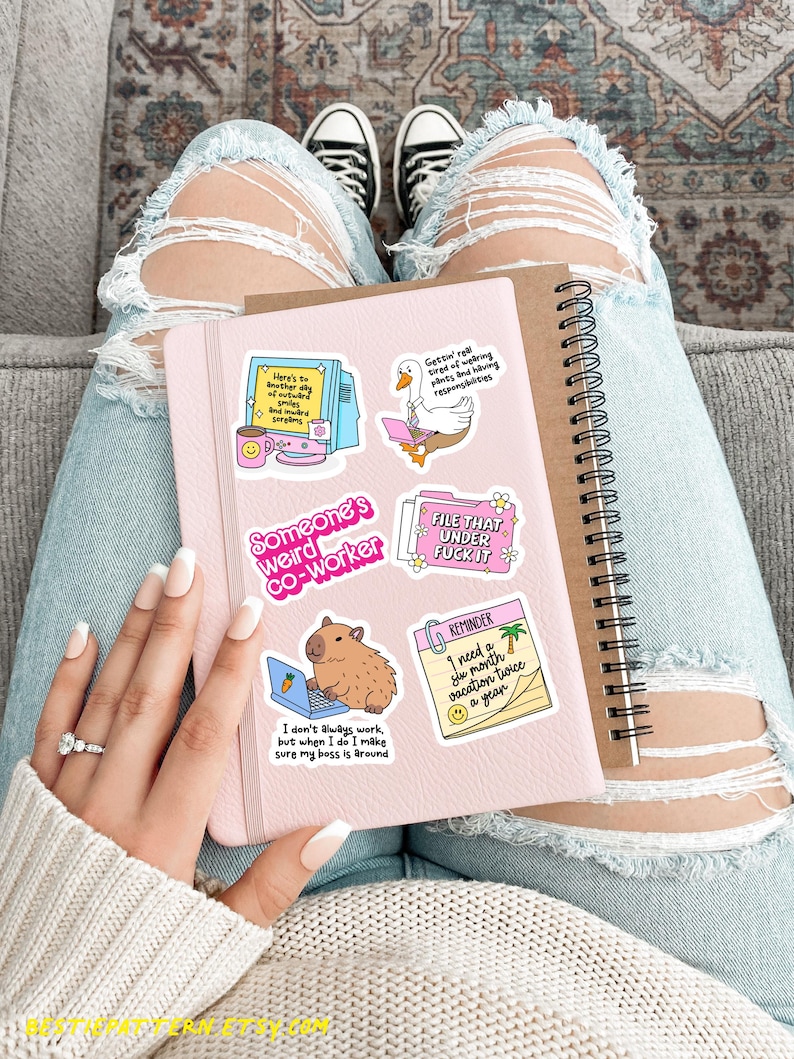 Puede incluir: Un cuaderno rosa con varias pegatinas, incluyendo un carpincho trabajando en un port&aacute;til y el texto: "I don't always work, but when I do I make sure my boss is around." Un cuaderno de espiral est&aacute; al lado.