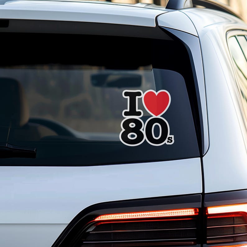 May include: A white car with a black and red sticker that says "I love 80s" on the rear window.
