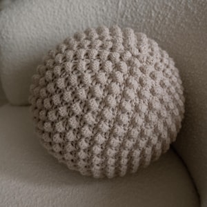 Handmade crochet bobble ball cushion in a round shape, featuring a textured bobble stitch pattern.