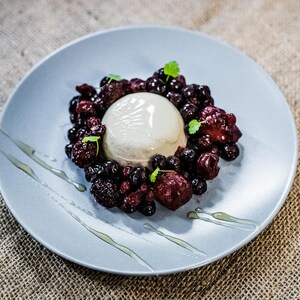 Könnte beinhalten: Ein weißer Panna Cotta-Nachtisch, belegt mit einer Mischung aus Brombeeren, Himbeeren und Blaubeeren auf einem hellblauen Teller.