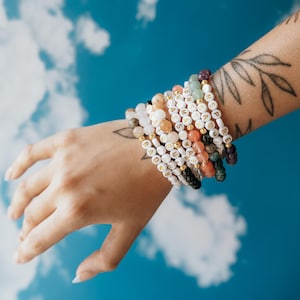 May include: A stack of colorful beaded bracelets with gold lettering spelling out words like "HOPE", "LOVE", and "PEACE".