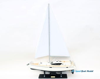 Può includere: Un modello di barca a vela bianca con una vela bianca e una base nera. Il modello è su uno sfondo bianco. "Speed Boat Model" è stampato sulla base.