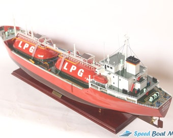 Può includere: Un modello di nave rosso e bianco con la scritta "LPG" sul lato. La nave è su una base di legno e ha un design dettagliato.