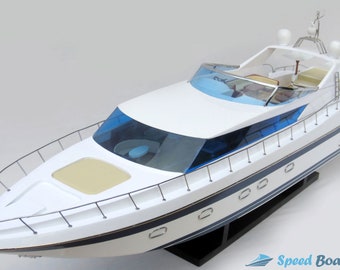 Può includere: Un modello di yacht bianco con accenti blu e una base nera. Lo yacht ha un grande parabrezza, un piccolo ponte e una ringhiera attorno al perimetro. Lo yacht è su una base nera.