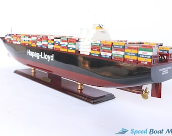Può includere: Un modello dettagliato di una nave portacontainer con scafo rosso e nero. La nave è carica di container colorati, molti dei quali hanno i loghi di compagnie di navigazione come Hapag-Lloyd, CMA CGM, OOCL e K Line. Il modello è su una base di legno.