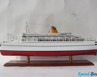 Può includere: Un modello di nave bianca con scafo rosso e camino giallo. La nave è su un supporto in legno con supporti dorati.