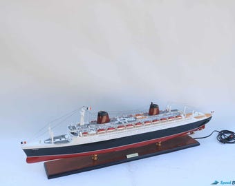 Può includere: Un modello dettagliato della nave da crociera France, con scafo nero e linea di galleggiamento rossa, sovrastruttura bianca e due fumaioli marroni. Il modello è montato su una base di legno e presenta dettagli intricati.