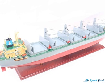 May include: A detailed model of a gray and red cargo ship with a yellow and blue superstructure. The ship has multiple cargo holds and is displayed on a wooden base.