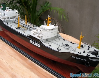 May include: A detailed model of a black and red tanker ship with the name "TEXACO NORGE" on the stern. The ship is on a wooden base and has a white superstructure with yellow accents.