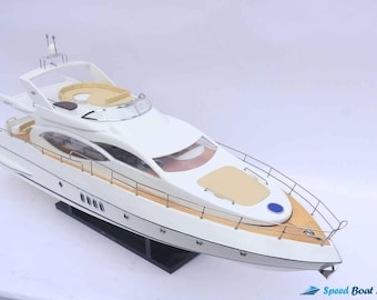 May include: A white and tan model yacht with a sleek design. The yacht features a wooden deck, a curved windshield, and a seating area. The model is displayed on a black stand. The image includes the text "Speed Boat Model".