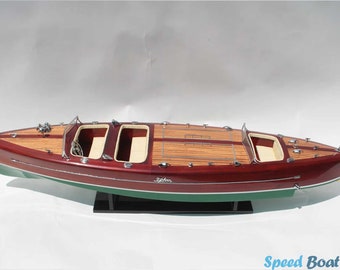 Può includere: Un modello di motoscafo in legno con scafo in mogano rosso, una striscia verde e un ponte bianco. Il modello ha una piccola bandiera americana sul retro e il nome "Tigress" è scritto sul lato.