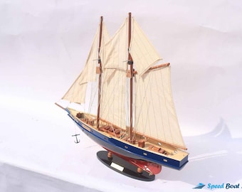 May include: A detailed model sailboat with a blue hull, tan sails, and wooden masts. The model features a red underside and is mounted on a black base. The sails are fully deployed, and the model includes an anchor.