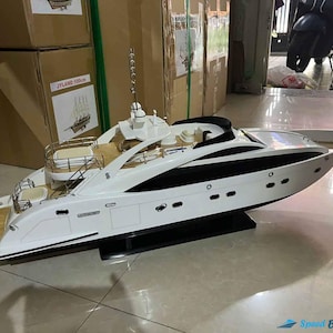 Peut inclure: Maquette de yacht blanc et noir au design épuré. Le yacht présente une bande noire sur le côté et un pont en bois. Il est présenté sur un socle noir. La maquette est une réplique détaillée d'un yacht de luxe.