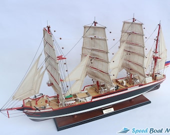 Può includere: Modello dettagliato di una nave alta con tre alberi e molte vele. La nave presenta uno scafo nero con accenti rossi e bianchi e un ponte di legno. Una piccola bandiera è visibile a poppa. Il modello è montato su una base di legno.
