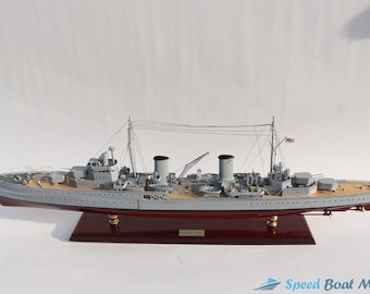 May include: A detailed model of a gray warship with a wooden deck and a red base. The ship has multiple gun turrets and a flag on the mast. The model is labeled "HMS " on the base.