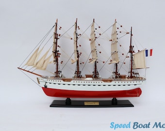May include: A detailed wooden model of the French sailing ship "France II" with white sails and a red hull. The model is displayed on a black wooden base with the name "France II" inscribed on it.