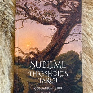 May include: A tarot deck titled "Sublime Thresholds Tarot" with a landscape illustration of a tree and a sunset. The cover also includes the text "Companion Guide" and the author's name, Nitasia Roland. The book is from Urania Press.
