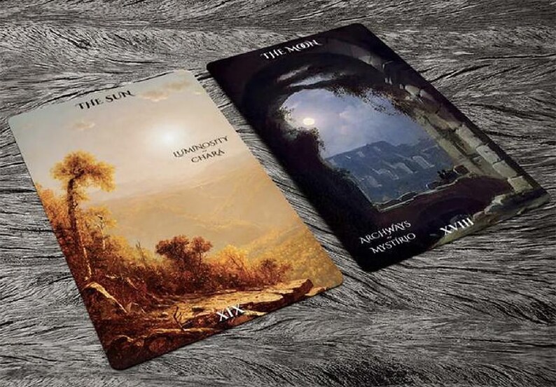 May include: Two tarot cards, "The Sun" and "The Moon", from the "Archways of Mystery" deck. The Sun card depicts a landscape with a large tree and a bright sky. The Moon card shows a dark, moonlit scene with an archway and a distant mountain range.
